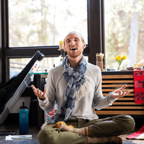 Person meditating and smiling indoors at New Living Expo.